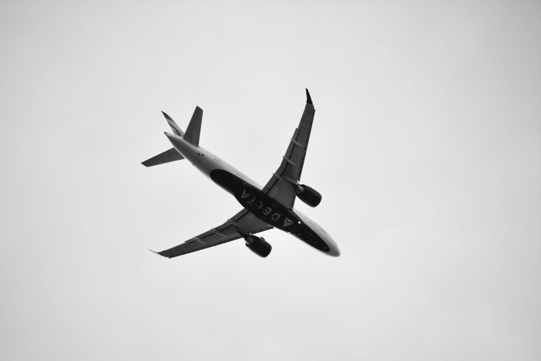 commercial airplane flying overhead in black and white